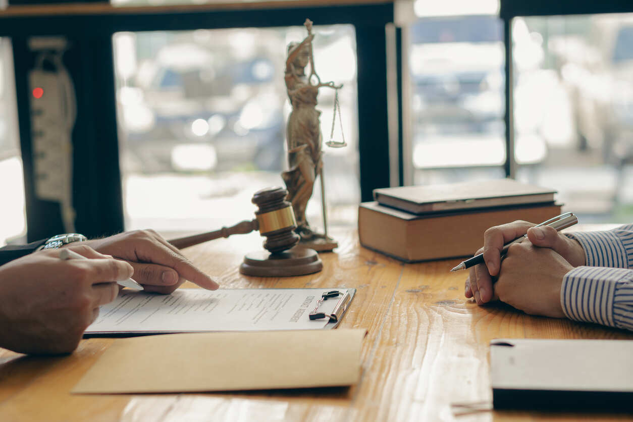 A lawyer explaining terms on a document to a client, highlighting legal support regarding California employment law for tech workers.