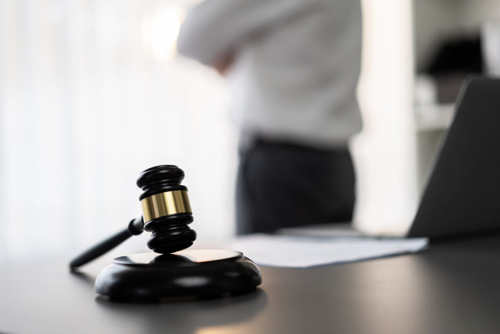 Gavel on desk symbolizing legal authority with a lawyer in the background, illustrating California employment law and legal support for entertainment industry professionals.